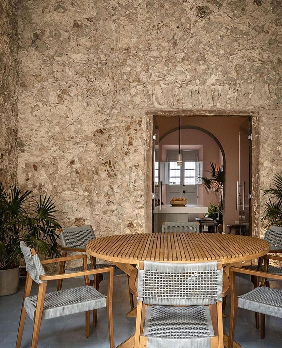 outdoor dining table, gray chairs, stone walls